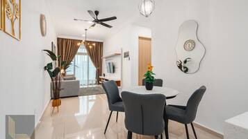 A modern dining area with a round table, four grey chairs, and a ceiling fan.