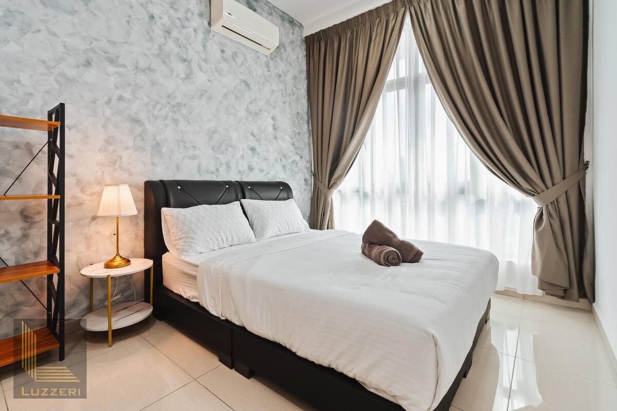Une chambre d’hôtel avec un mur décoré d’un motif imitant le marbre, un lit avec une literie blanche, une table ronde avec une lampe et une fenêtre avec des rideaux.