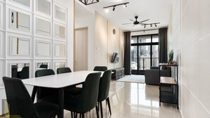 A modern dining area with a white table, black chairs, a ceiling fan, and a city view through large windows. - Legasi Kampung Bharu Guesthouse (Kuala Lumpur)
