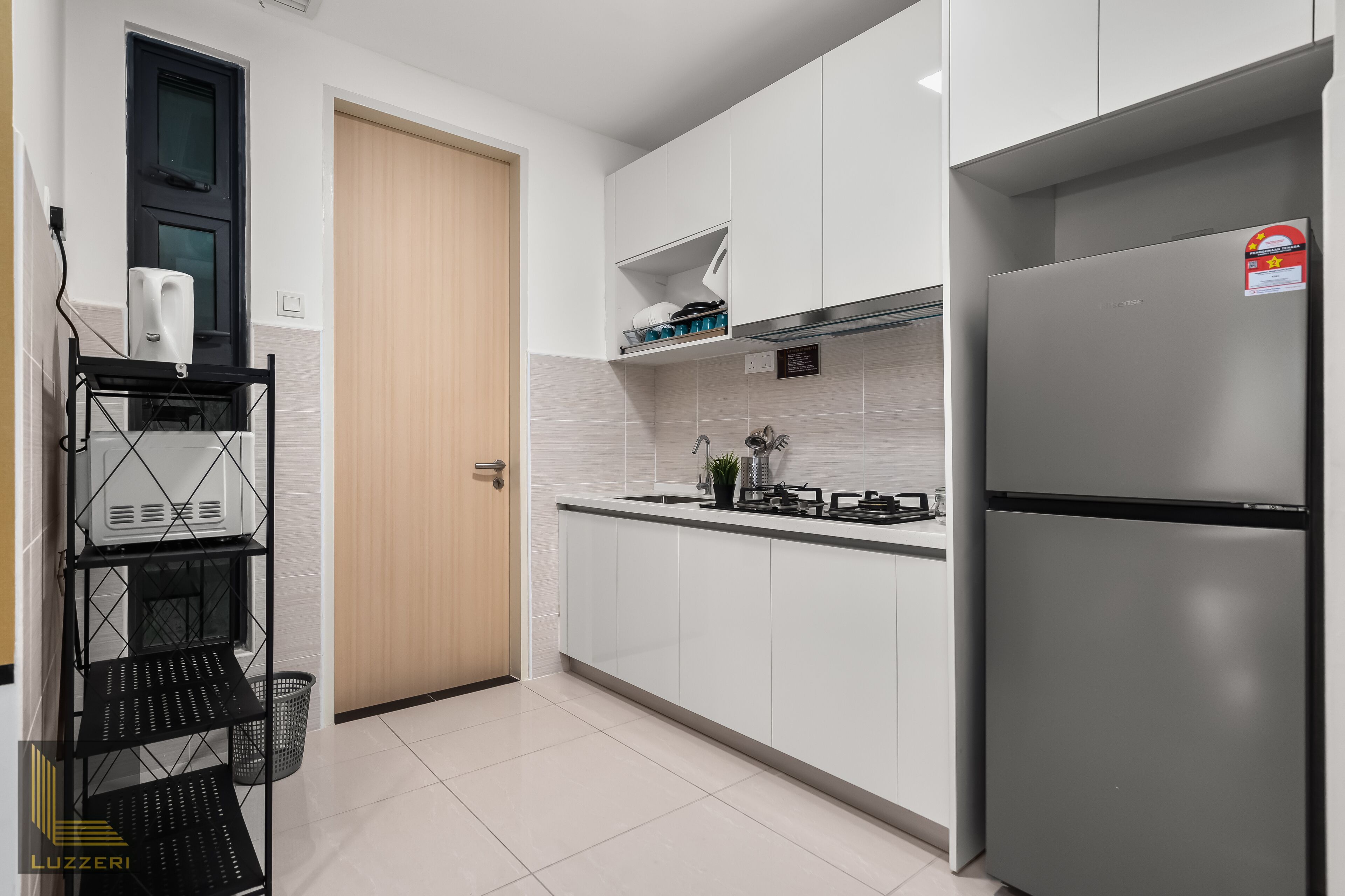 A modern kitchen with white cabinets, a stainless steel refrigerator, and a black metal rack with shelves.