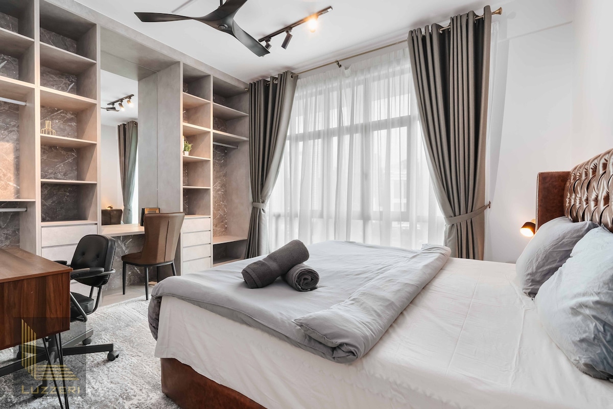 Ett modernt hotellrum med en stor säng, ett skrivbord och inbyggda hyllor.