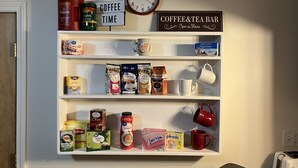 A coffee shelf with various brands and types of coffee, tea, and mugs. - Cozy Newmarket Escape! Wine & WiFi! Full Kitchen! (Newmarket)