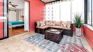 Una sala moderna con sofá, una mesa de centro y vista a un dormitorio a través de una puerta de vidrio.