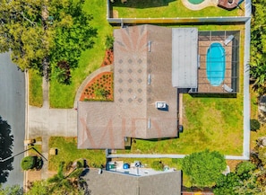 Vue aérienne d’une propriété résidentielle dotée d’une piscine, d’un patio couvert et d’un jardin aménagé.