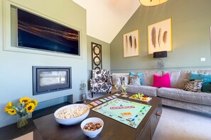 A living room with a sofa, a coffee table with board games, a bowl of popcorn, and a vase of sunflowers.