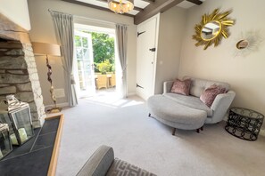 A spacious living room with a grey sofa, a stone wall, a large window, and a chandelier.