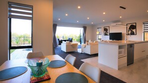 Uma sala de estar moderna com área de jantar, cozinha e varanda com vista.
