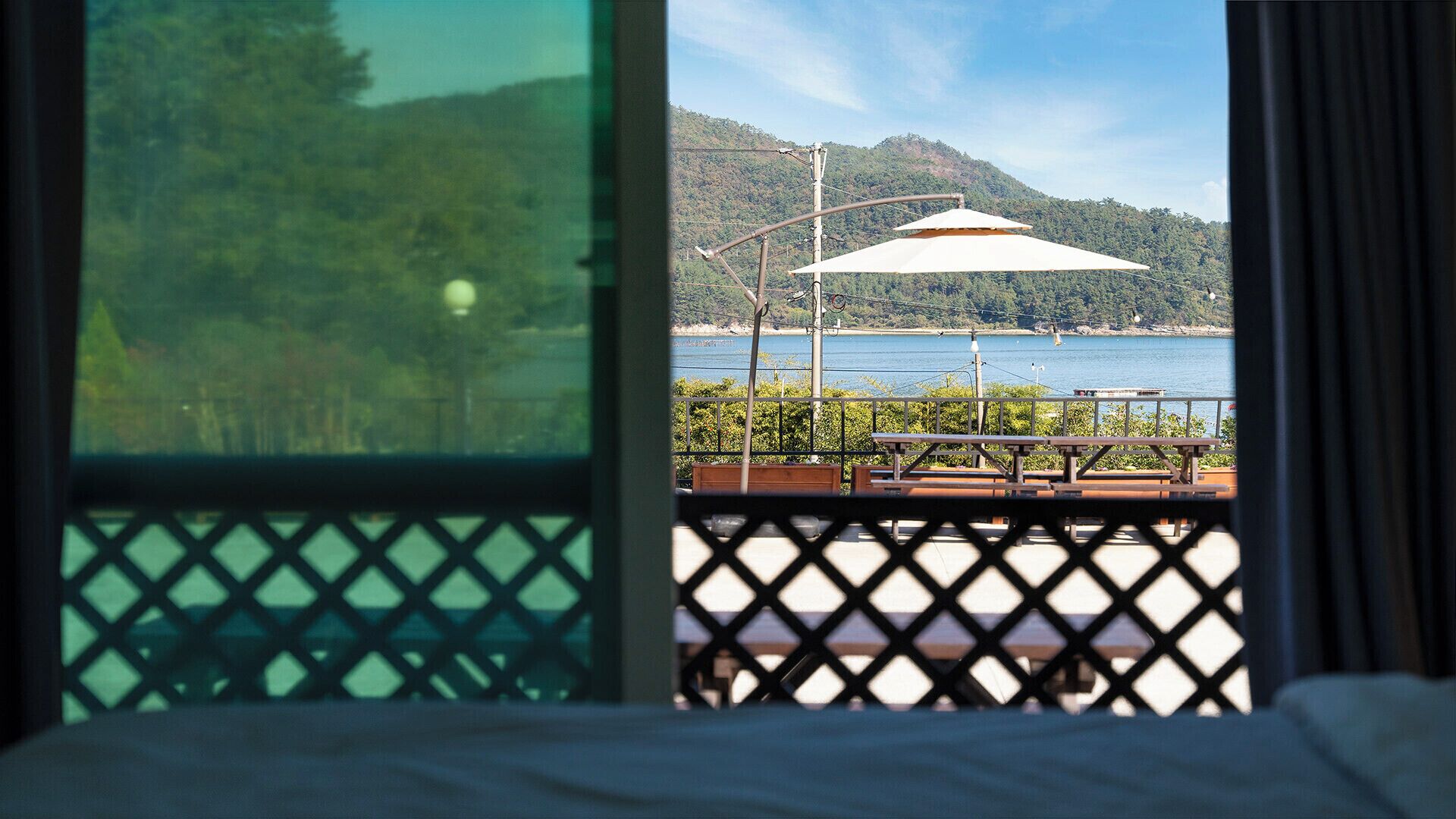 Una habitación con vista a un lago, una terraza de madera y una montaña al fondo.