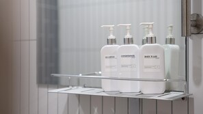 A bathroom shelf with three bottles of shampoo, conditioner, and body wash. - Namhae Seven House (Namhae)