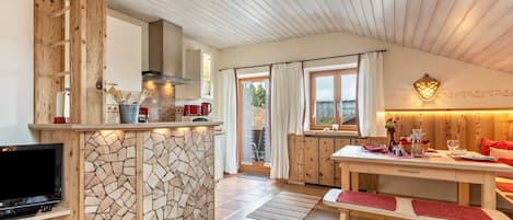 A modern kitchen with a stone backsplash, wooden cabinets, and a built-in TV.