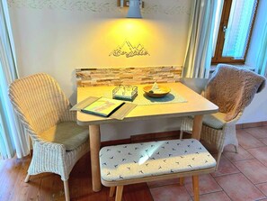 Een gezellige kamer met rieten stoelen, een klein houten tafeltje, een bank en een wandlamp.