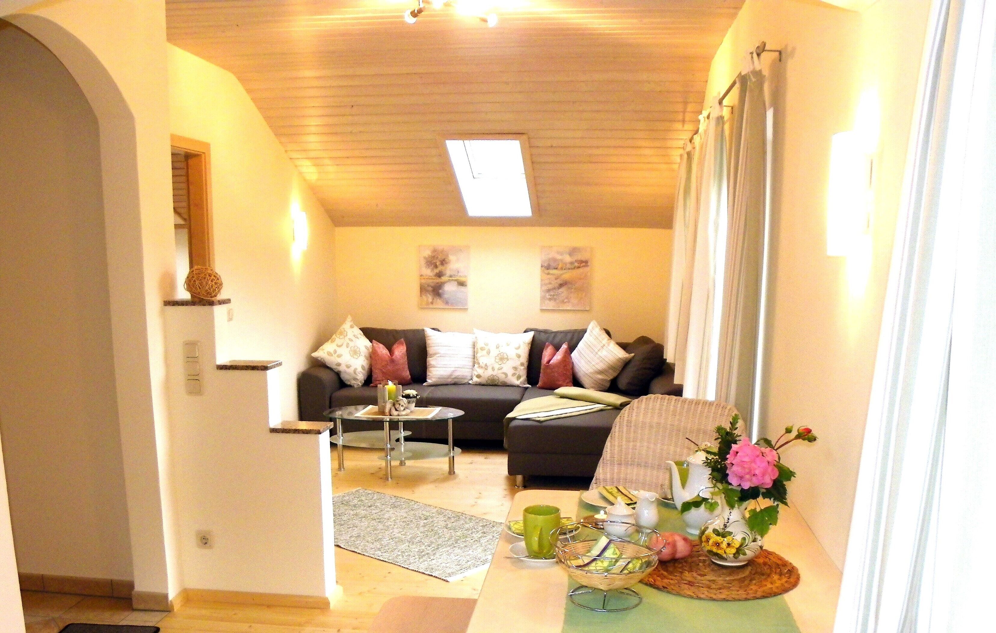 Un salon avec un canapé, une table basse et une petite table sur laquelle est posé un vase.