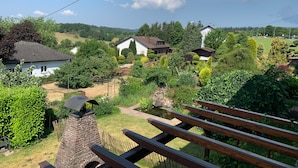 A residential area with houses, a stone barbecue structure, and a wooden bench. - Apartment "Draußen am See" with Private Sauna, Garden & Wi-Fi (Losheim)