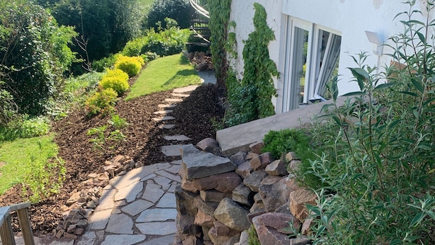 A stone pathway leading to a white building with a garden view. - Apartment "Draußen am See" with Private Sauna, Garden & Wi-Fi (Losheim)