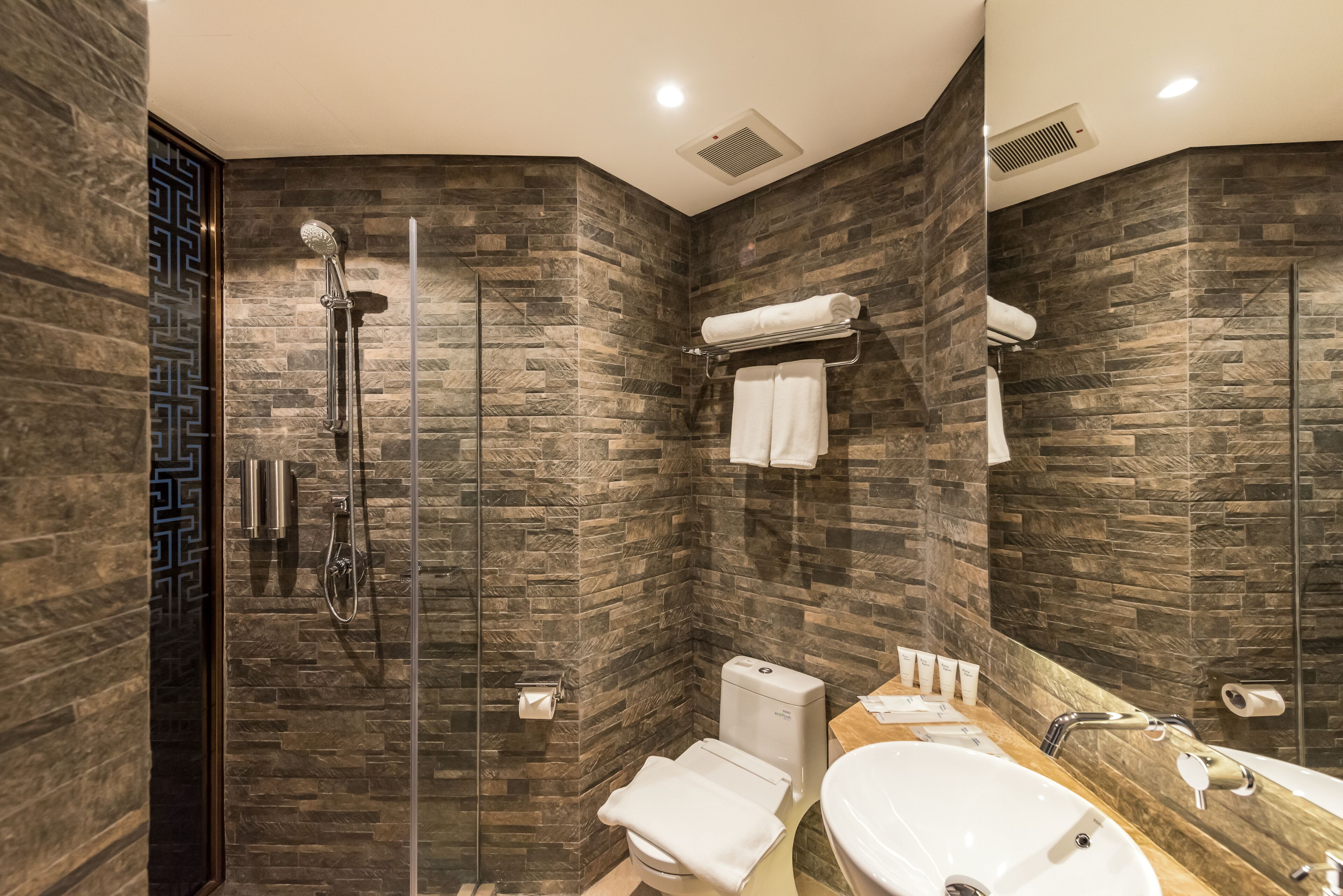 Un baño moderno con ducha envuelta en vidrio, inodoro y lavabo con tocador.