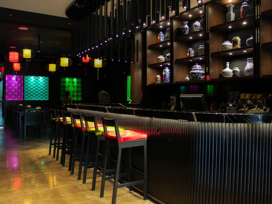 Zona de bar con taburetes y estantes llenos de jarrones decorativos.