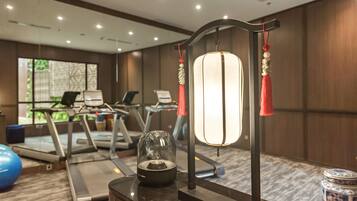 A hotel room with exercise equipment, a decorative lamp, and a view of the outdoors.