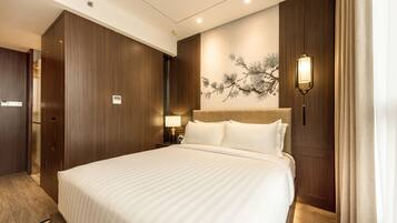A hotel room with a large bed, wooden paneling, a wall-mounted lamp, and a nightstand with a lamp.