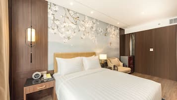 A hotel room with a large bed, a nightstand with a lamp, a chair, and a decorative wall with floral patterns.