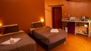 Ein Zimmer mit zwei Betten, einer Küchenzeile und Holzboden.