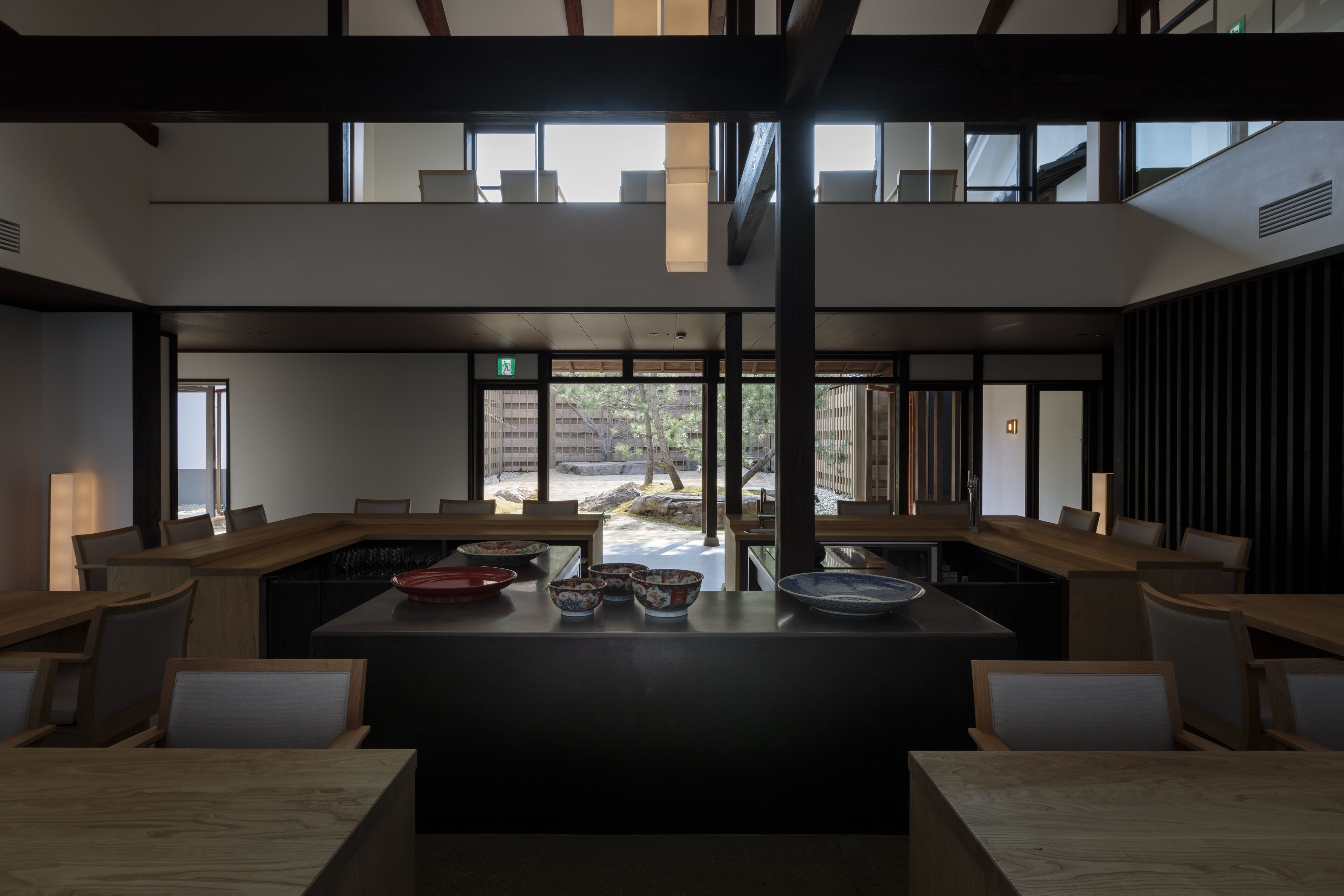Un comedor moderno con una isla central, mesas y sillas de madera.