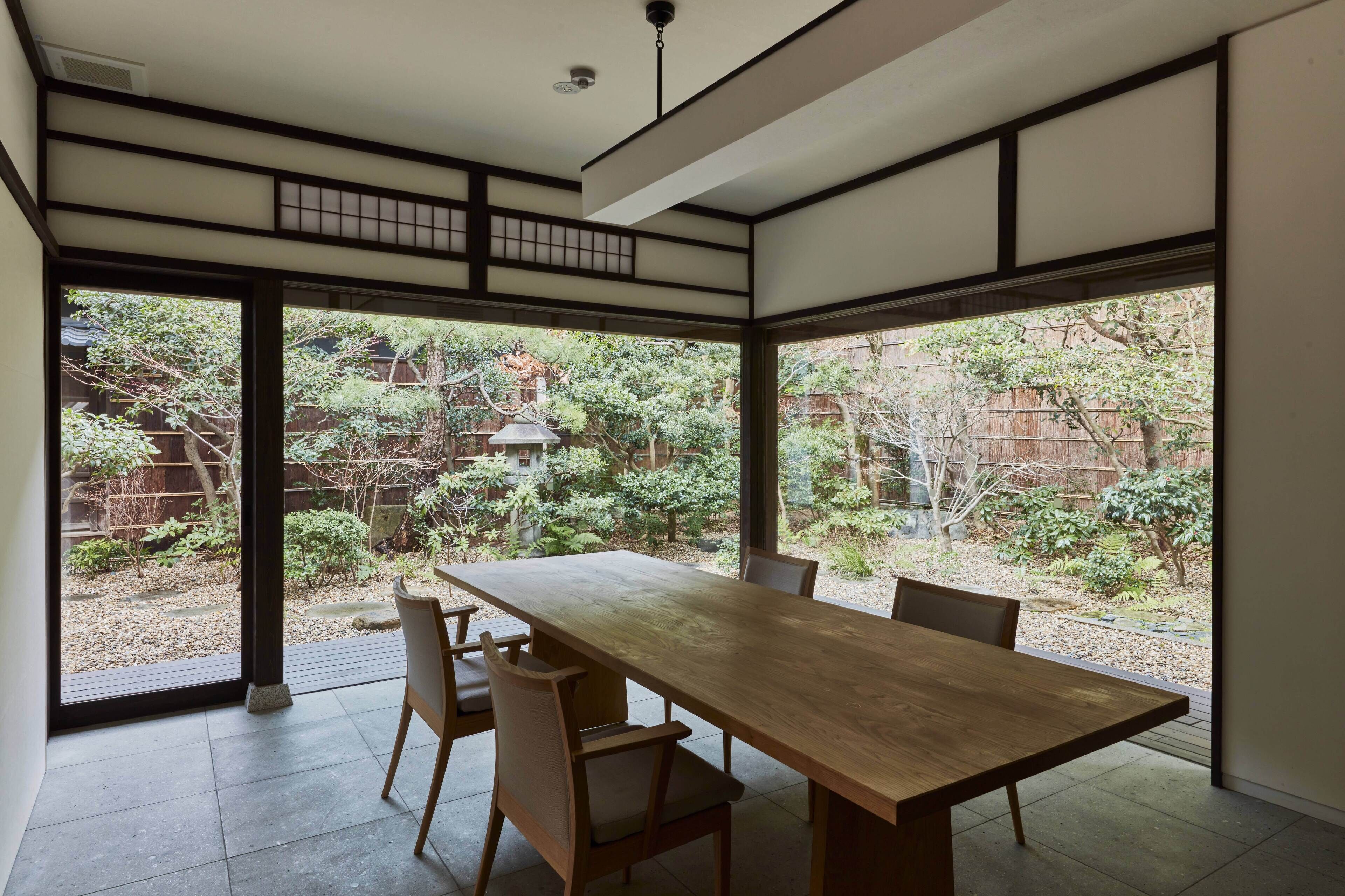 A traditional Japanese-style room with tatami flooring, a low wooden table, and sliding doors leading to a garden.