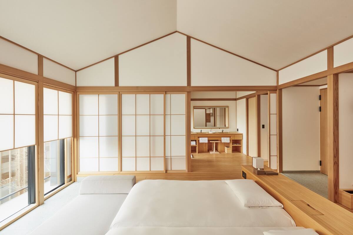 A traditional Japanese-style room with tatami flooring, a wooden bed, a washbasin, and a large window.