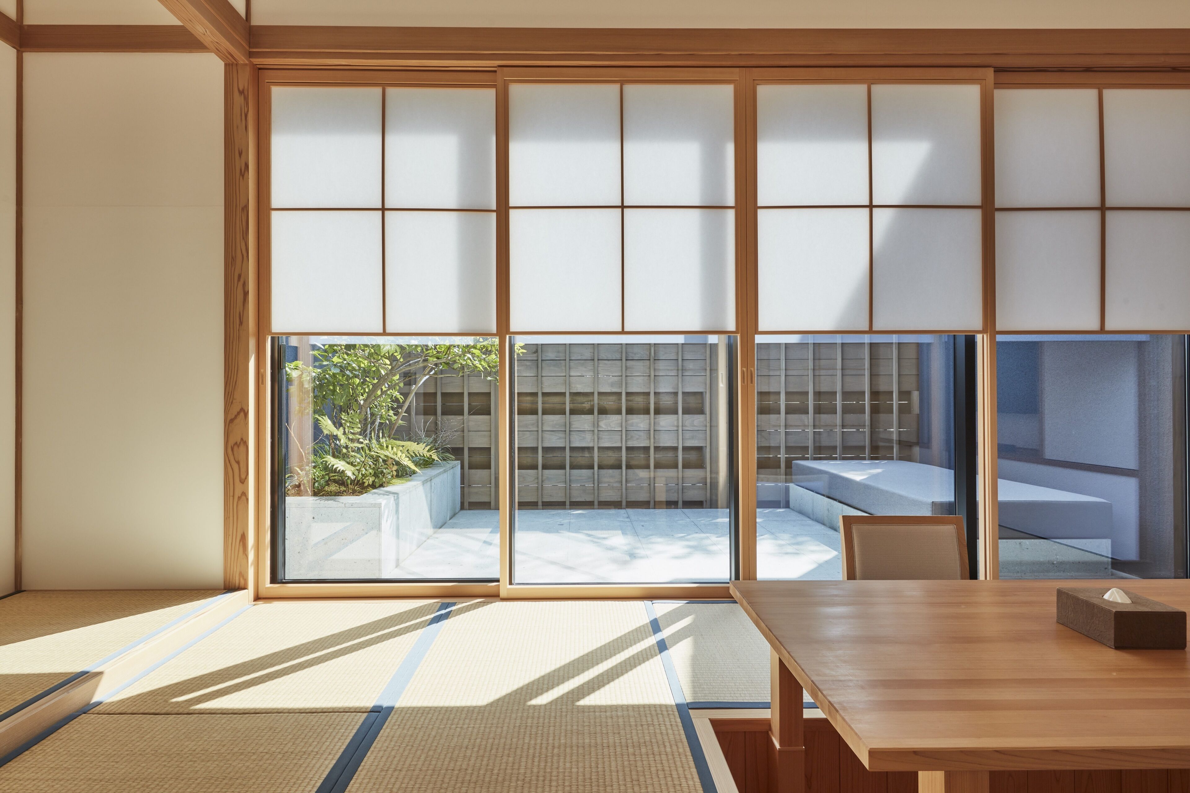 A traditional Japanese room with tatami flooring, sliding shoji doors, and a view of a garden.