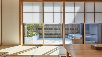 A traditional Japanese room with tatami flooring, sliding shoji doors, and a view of a garden.