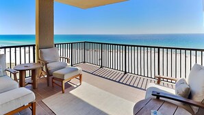 Un balcon donnant sur la plage, aménagé avec des chaises et une petite table.