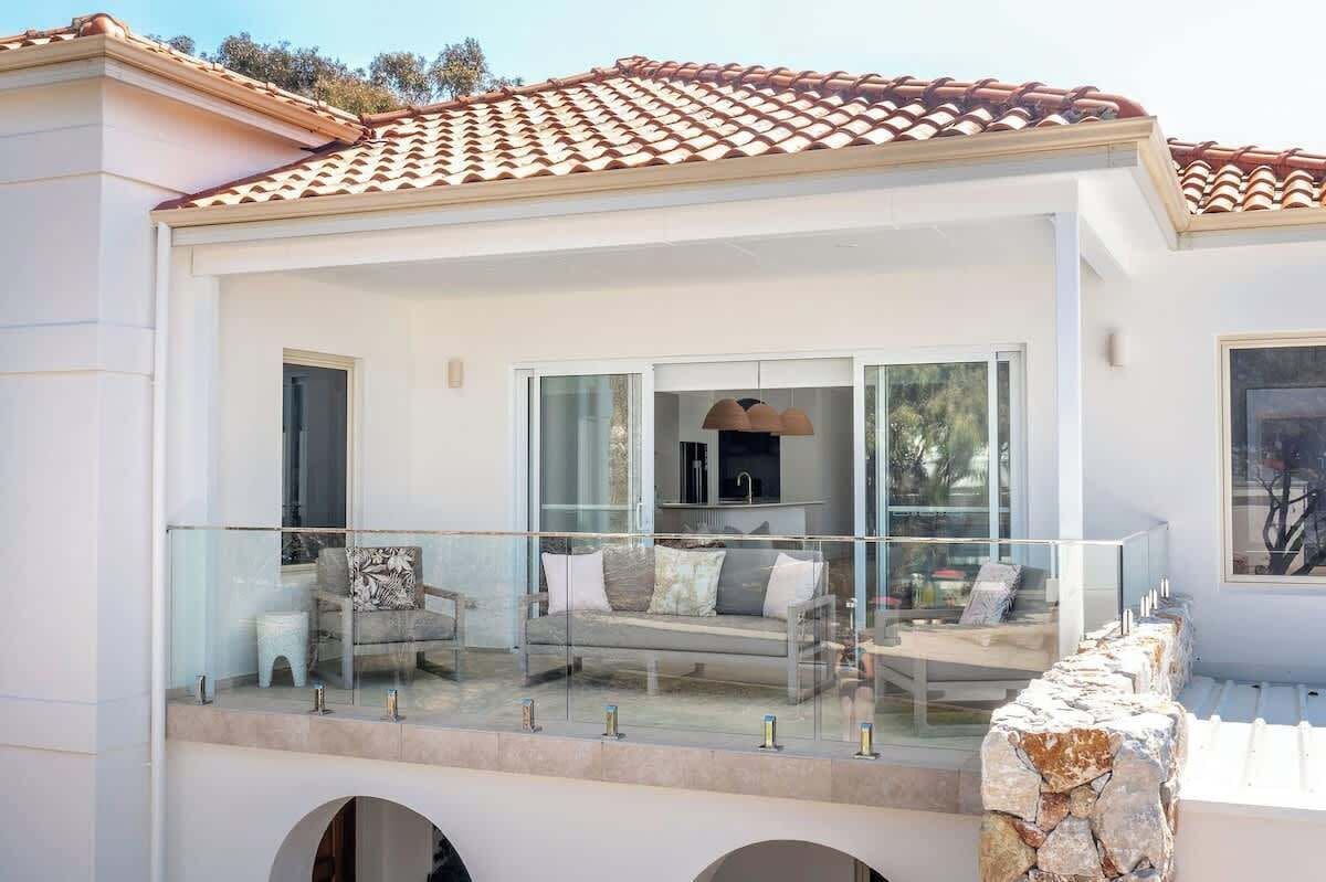 A modern house with a balcony, a sofa, and a dining area.