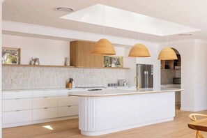A modern kitchen with a central island, pendant lighting, and a built-in oven.