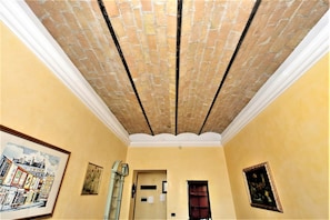 Una stanza con soffitto a motivo di mattoni, una parete gialla e opere d'arte incorniciate.