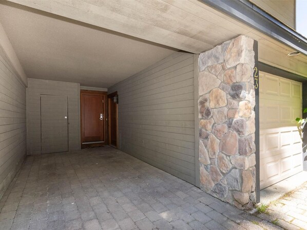 A garage with a stone accent wall, a wooden door, and a paved driveway.