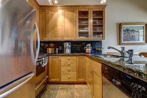 A kitchen with wooden cabinets, a stainless steel refrigerator, a Bosch dishwasher, and a granite countertop. - Telemark 23 - Ski in Walk out, Private Sauna, Short Walk to the Village (Whistler)
