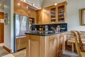 A kitchen with wooden cabinets, a stainless steel refrigerator, a microwave, and a coffee maker.