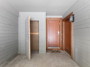 A hallway with a wooden door, a white door, and a small rug on the floor.