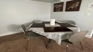 Un comedor con una mesa redonda, cuatro sillas y dos obras de arte en las paredes.