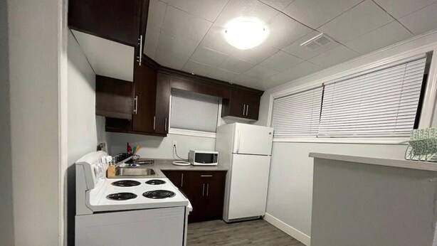 Una cocina compacta con estufa, microondas y refrigerador blancos.