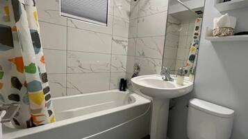 Een bad/douchecombinatie, een haardroger, handdoeken, zeep