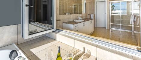 A modern bathroom with a glass shower enclosure, a large mirror, and a bathtub.