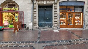 A street view with a bookstore named 'Nomo' and a shop with a sign 'pomme d'api'. - Beautiful and very quiet historical apartment located in the hyper center (Montpellier)
