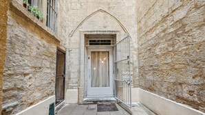 A narrow alleyway with a stone wall, a metal gate, and a door with a glass panel. - Beautiful and very quiet historical apartment located in the hyper center (Montpellier)