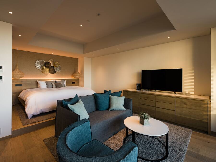 Ein modernes Hotelzimmer mit Bett, Sofa, Fernseher und einem kleinen Tisch.