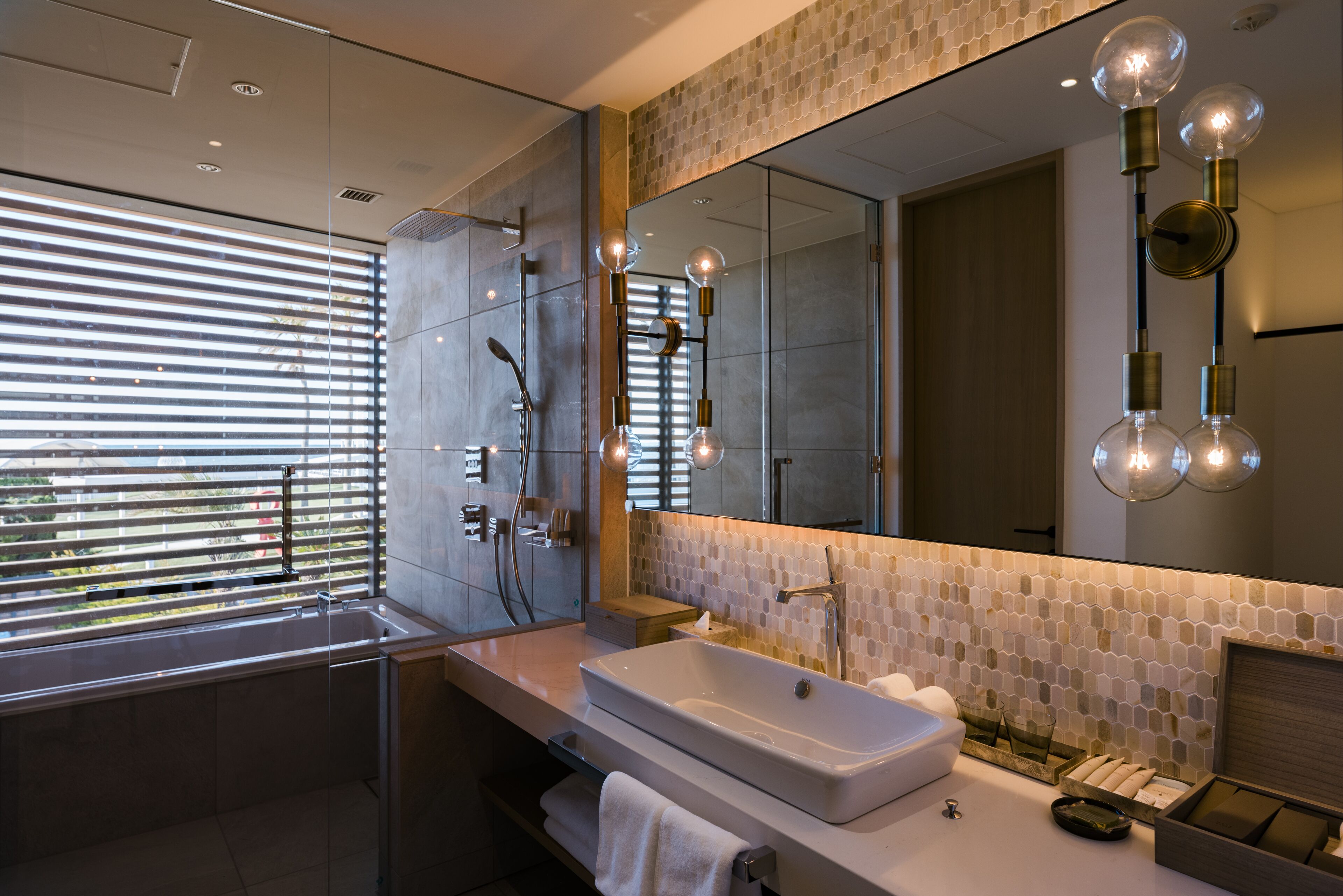 Un baño moderno con un espejo grande, un lavabo y una ducha.