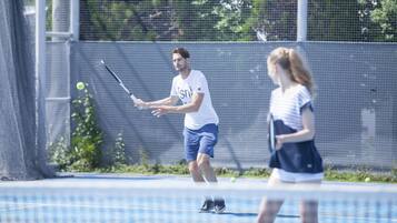 A tennis court with a net in the middle, surrounded by a fence.