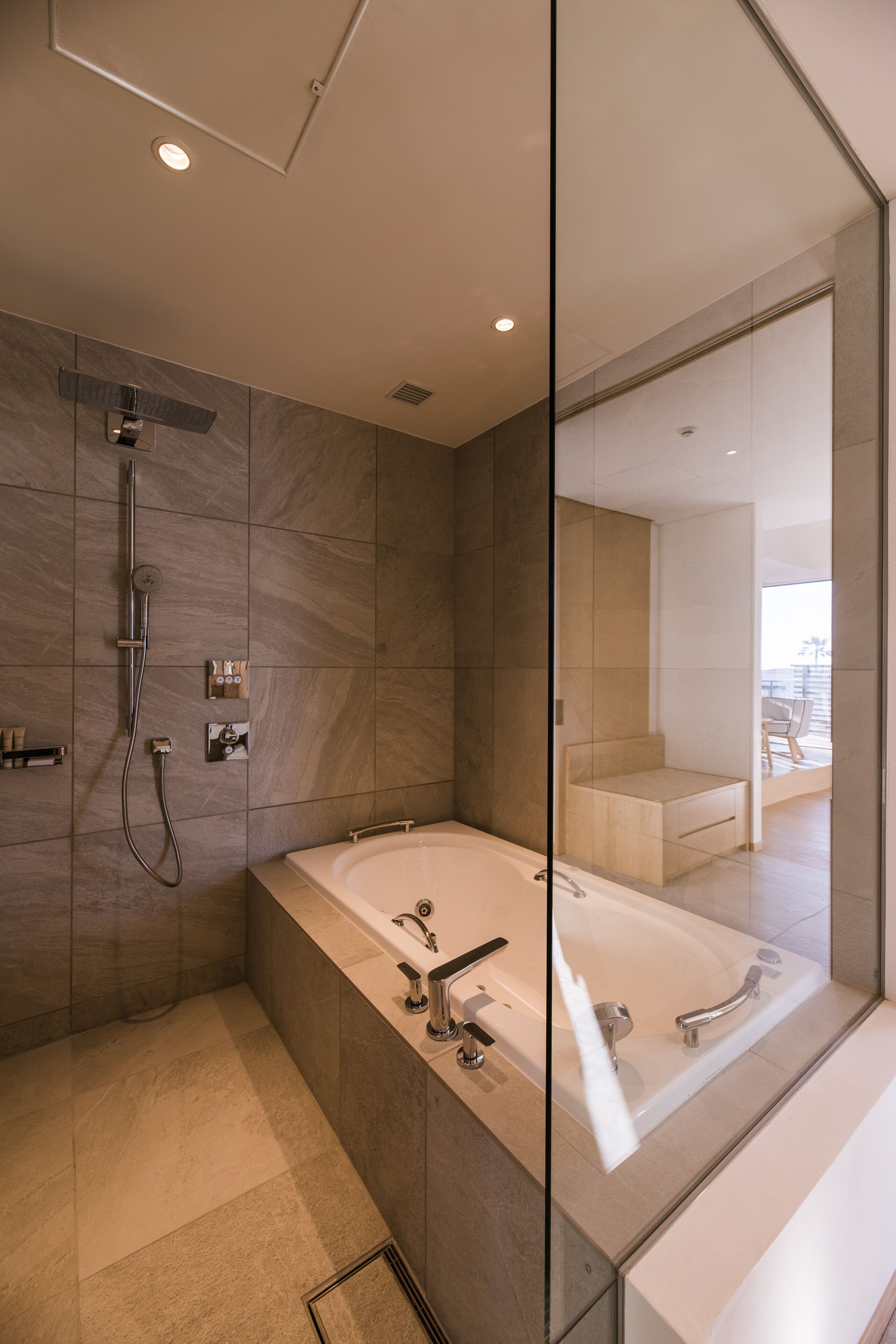 Un baño moderno con una bañera grande, zona de ducha y mampara de cristal.