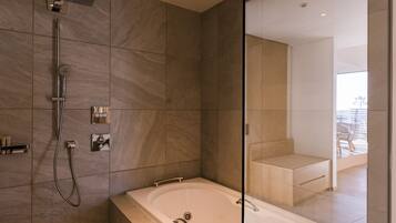 Un baño moderno con una bañera grande, zona de ducha y mampara de cristal.
