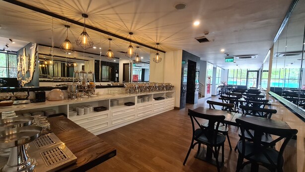 A restaurant with a long counter, hanging pendant lights, and a view of the outdoors through large windows. - d'primahotel Bintan (Bintan)