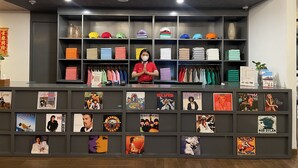 A store with shelves of hats and folded clothes, and a counter with posters. - d'primahotel Bintan (Bintan)